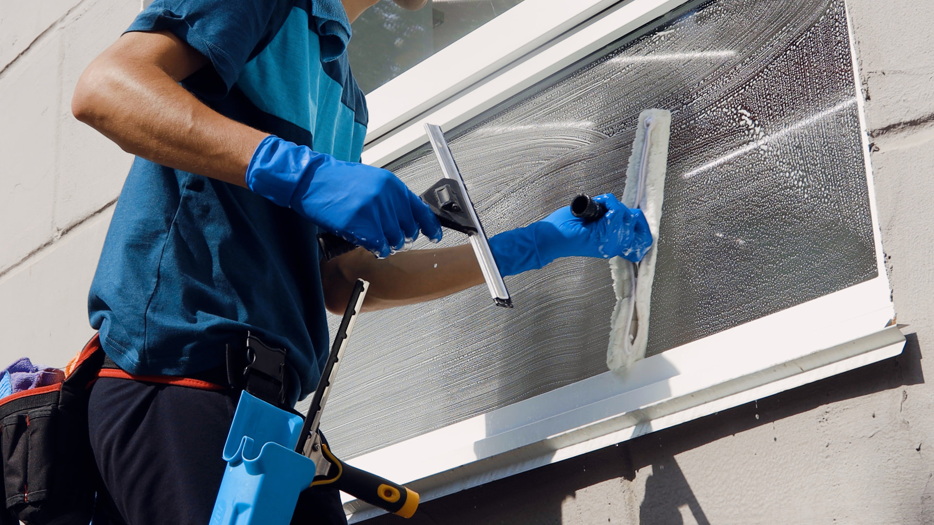 Window cleaner washing a window with a squeegee
